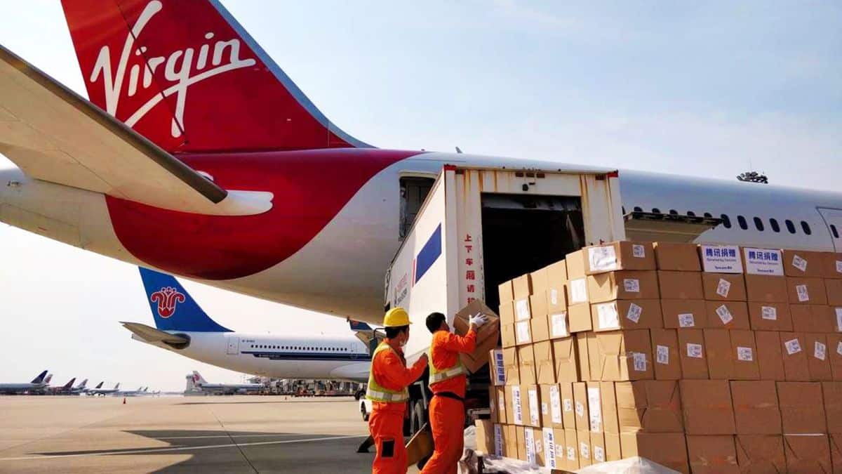 Boxes being loaded in rear door of plane with red tail.