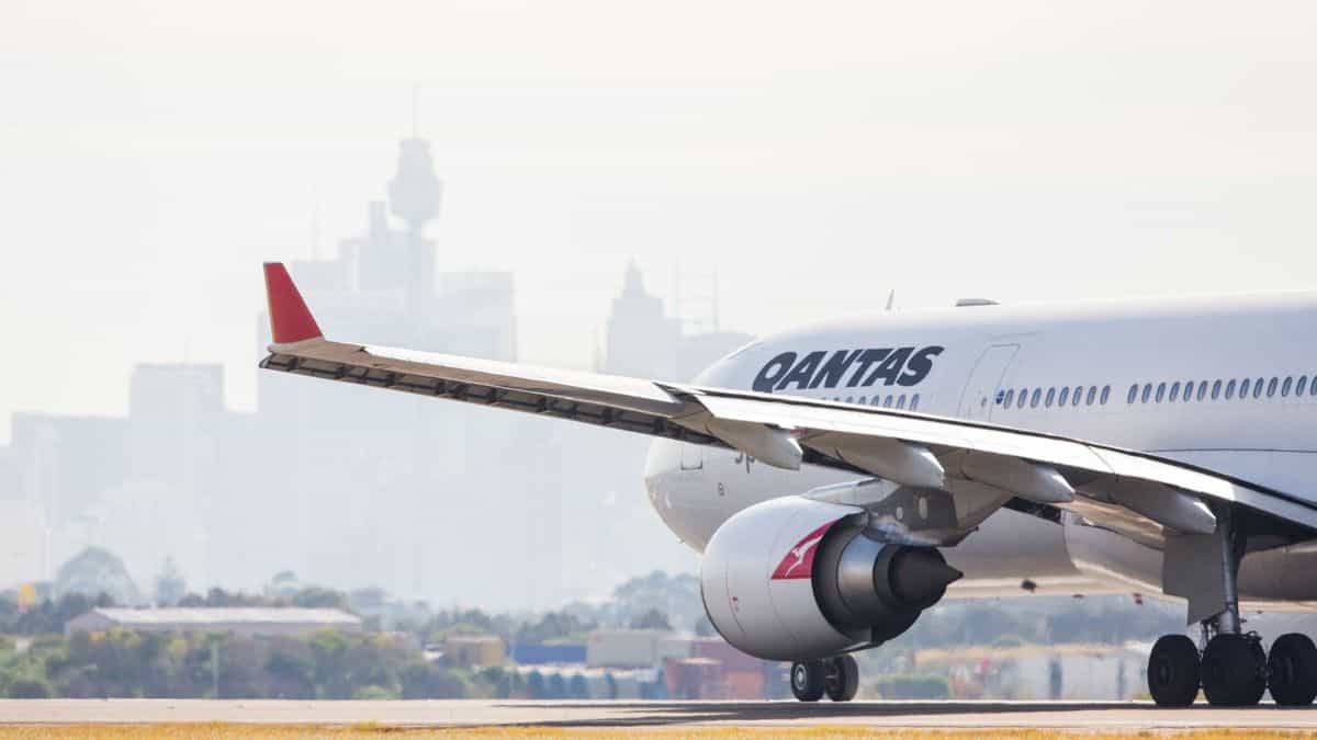 View from behind the wing of a big white jet, looking in at an angle as plane moves down runway