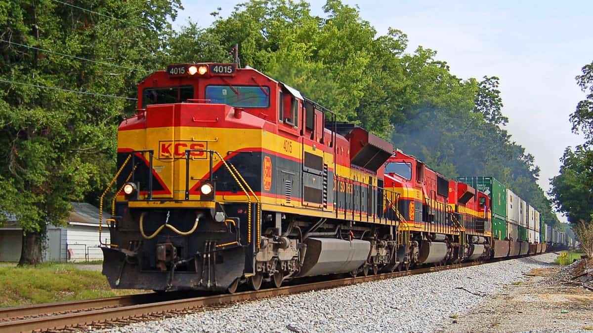 A photograph of a train locomotive passing by some trees.