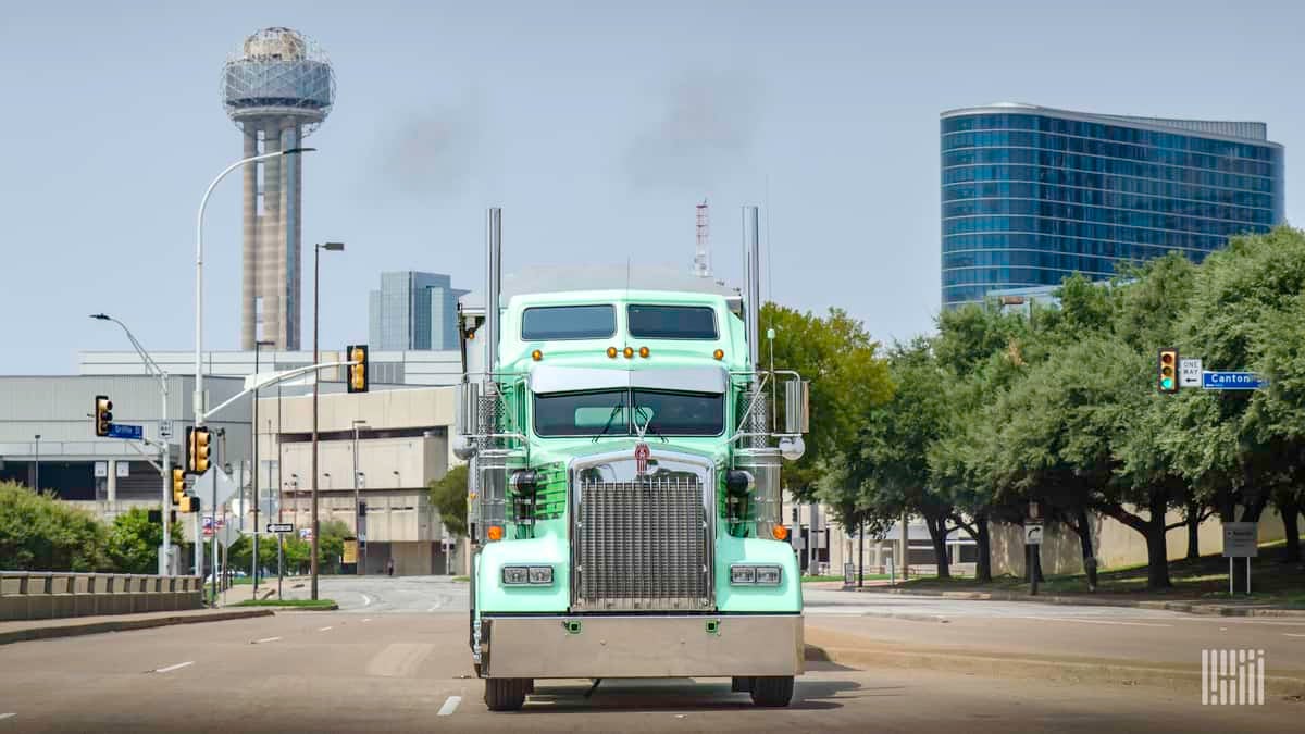 Front view of sea green truck driving on empty city street