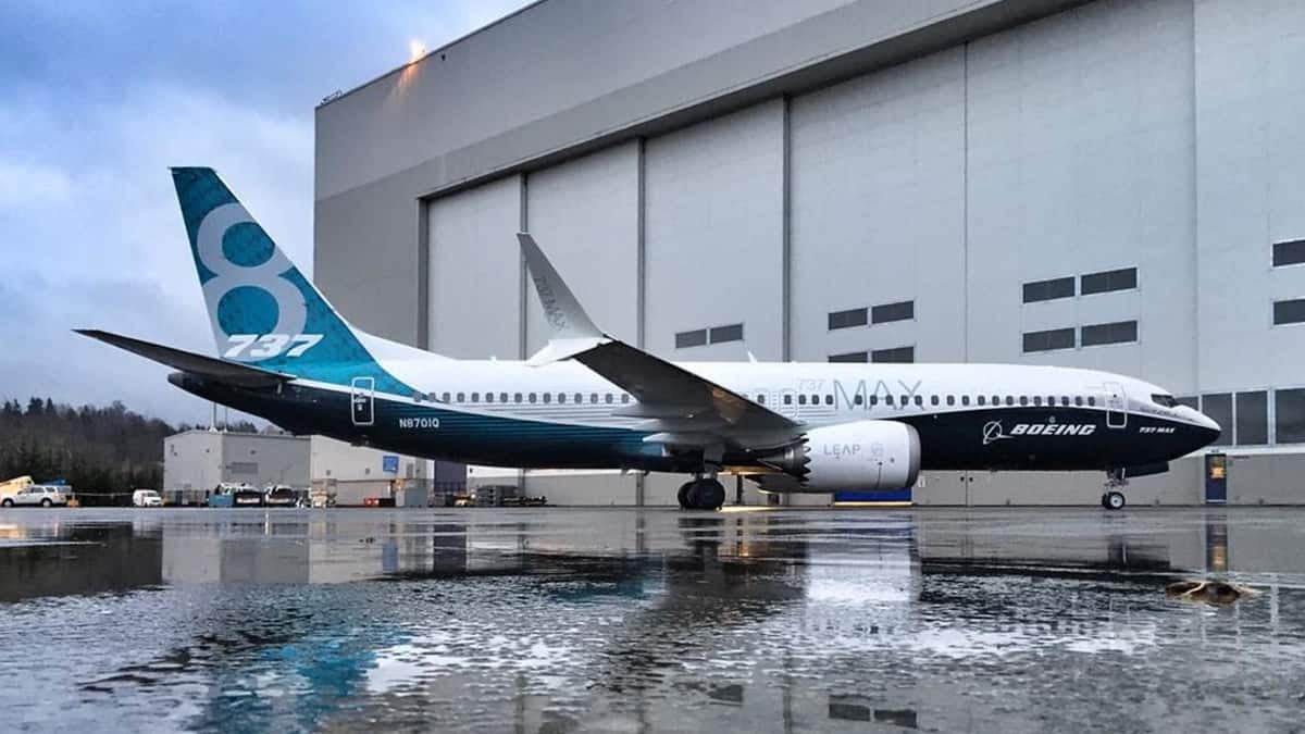 A blue and white 737 MAX next to a hangar at a Boeing facility.