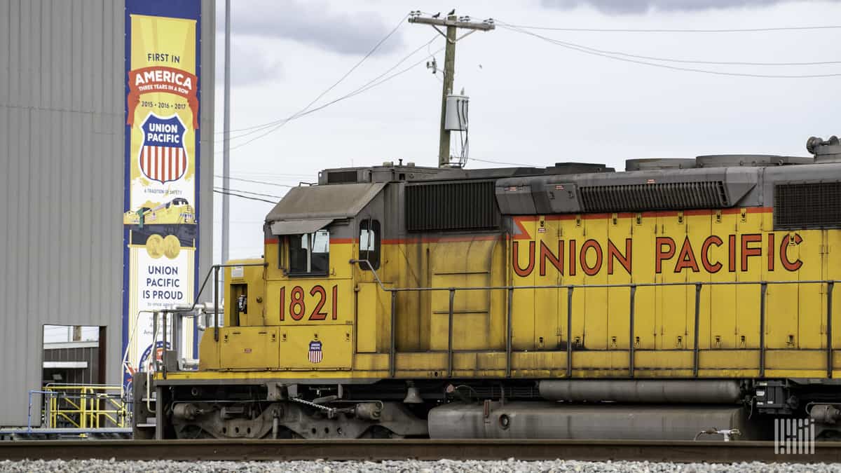 A photograph of a train locomotive by a buidling.