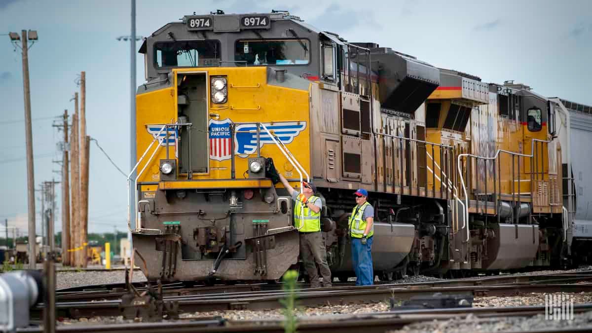 A photograph of two men in front on a train locomotive.