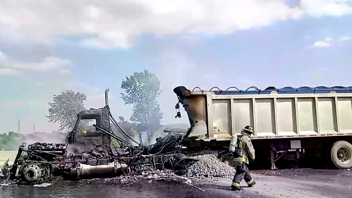 A firefighter walks by a burnt-out tractor-trailer on Ontario Highway 401 near toronto Canada