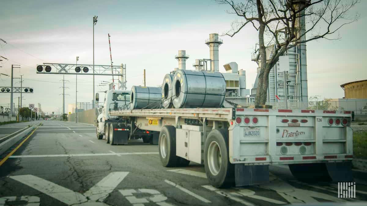 A truck hauls metal in a flatbed trailer. Renewed tariffs on aluminum imports from Canada could impact speciality cross-border trucking.