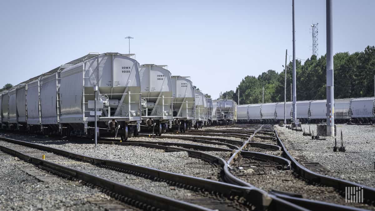 A photograph of a rail yard. There are several lines of trains parked at the yard.