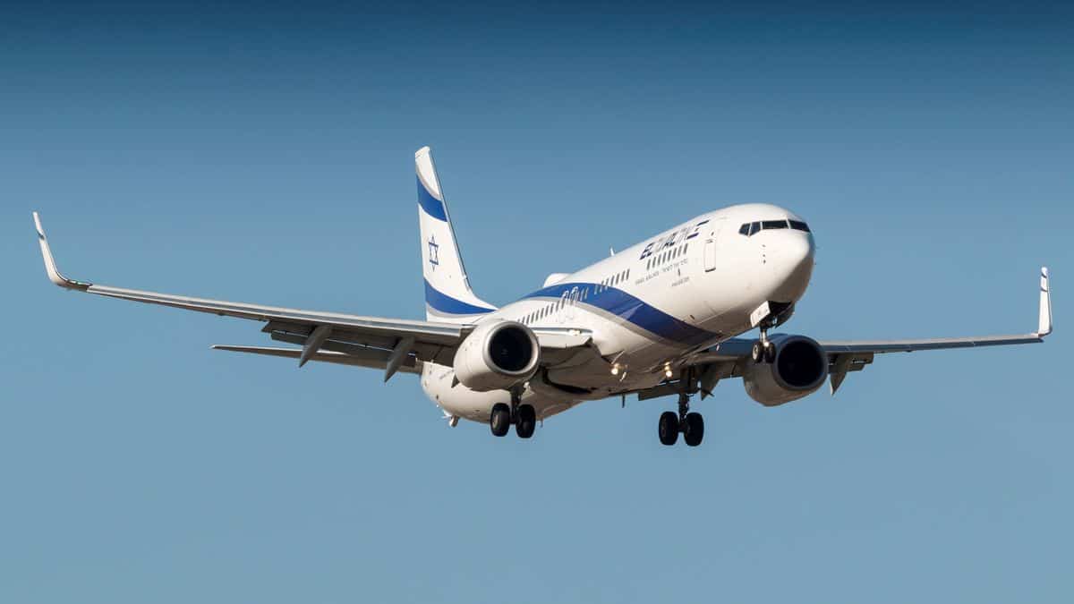 A white jet approaching for landing with wheels down.