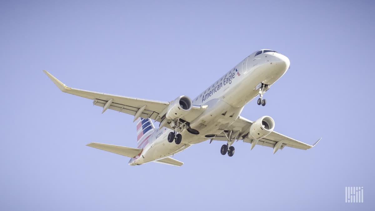 Looking up at a silver plane overhead coming in for landing at airport.