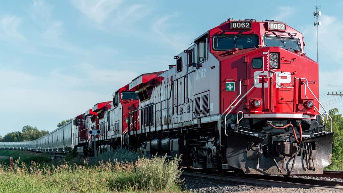 A photograph of a Canadian Pacific train traveling through a grassy field.