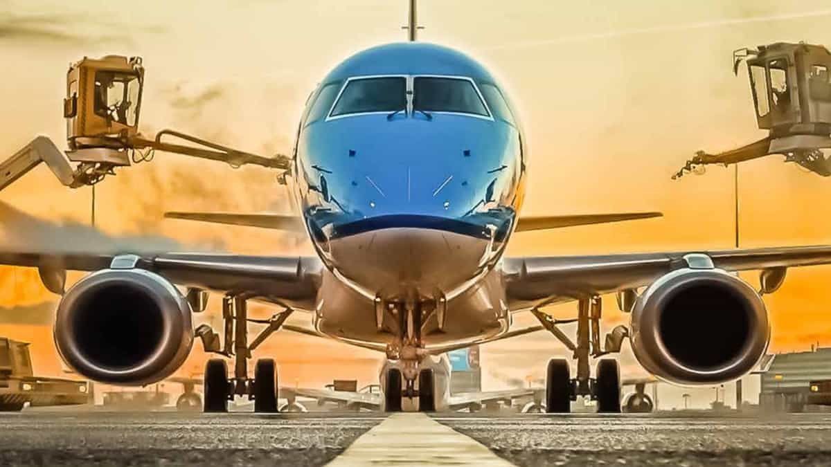 Shiny blue plane coming straight at camera, with morning sun in the background.