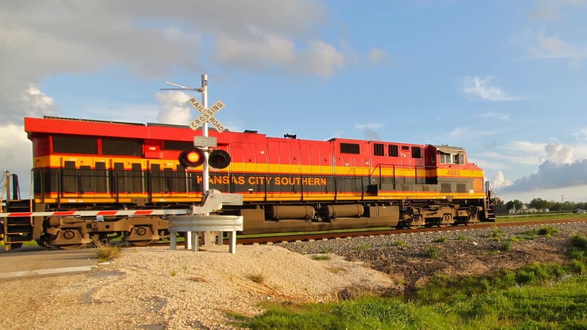 A photograph of a train passing through a rail grade crossing.