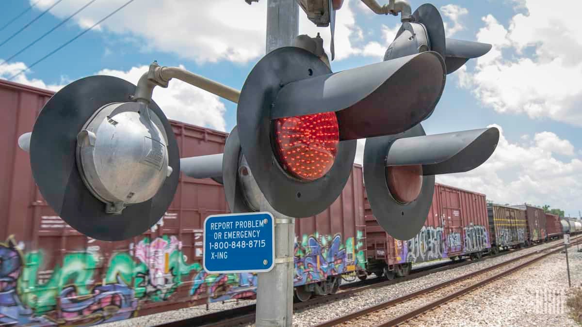 A photograph of a train at a railroad crossing.