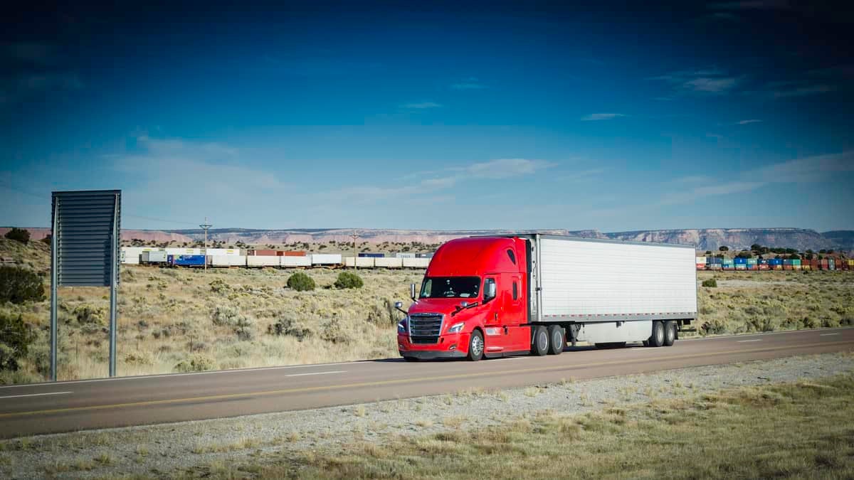 Truck on highway with intermodal train in the background