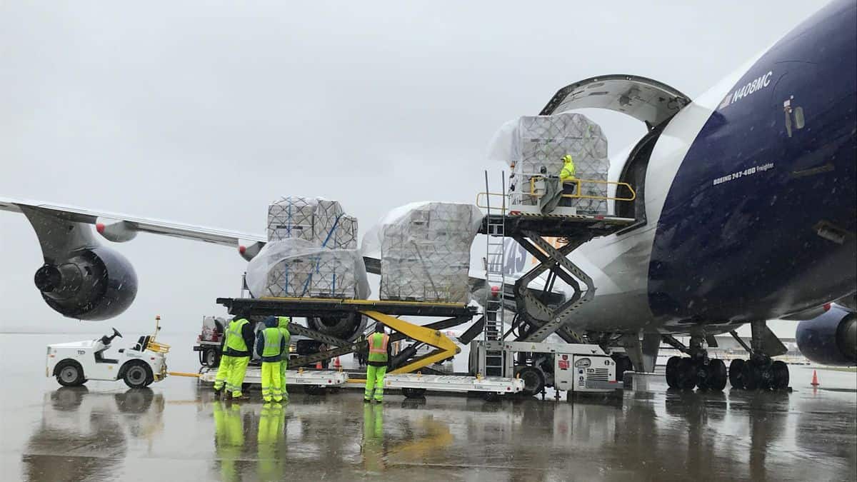 Big cargo plane being unloaded in the rain at airport.