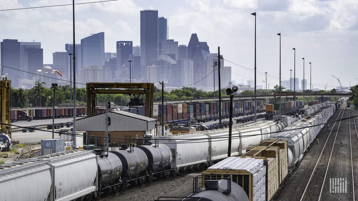 A photograph of rail yard. A city with skyscrapers is in the background.