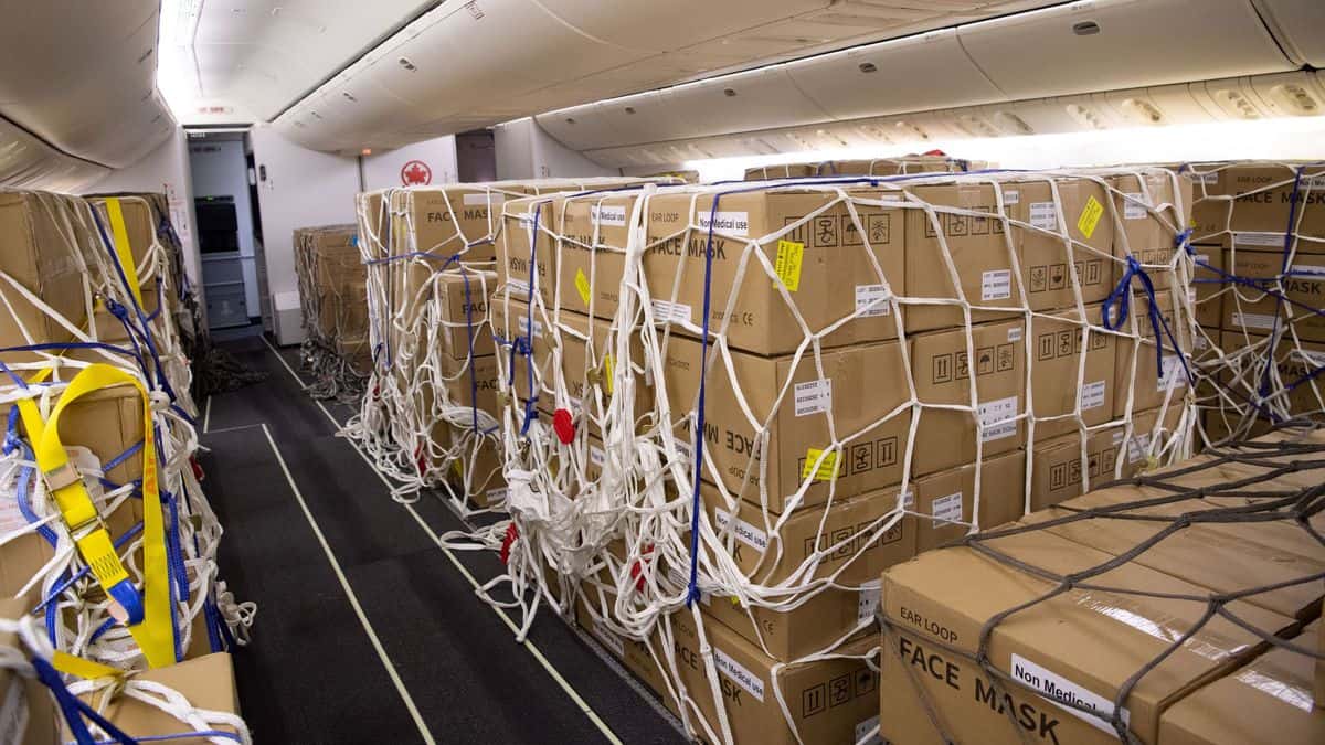 Boxes of face masks and tied down with nets on the passenger cabin floor of plane after seats were removed. Air Canada was faster than U.S. airlines to modify planes for this type of cargo operation.