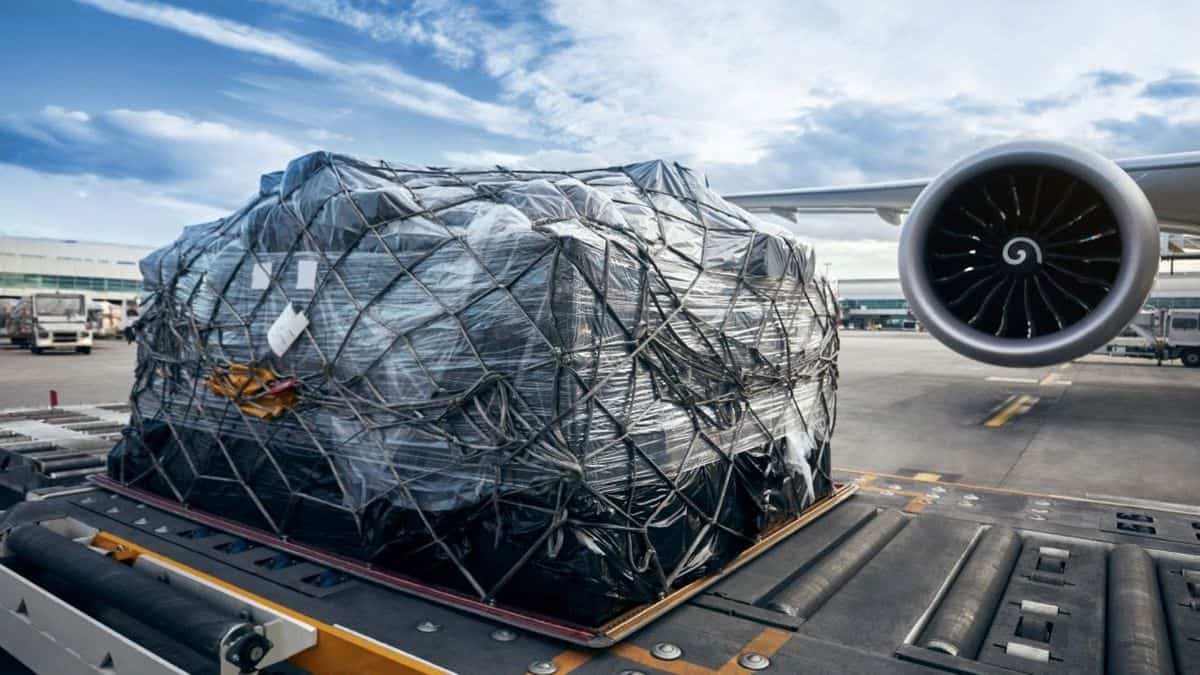 A large shipment tied down on a pallet that is sitting by the engine of a large aircraft, with a bright blue sky in the background. Air cargo prices are 60% higher this year.