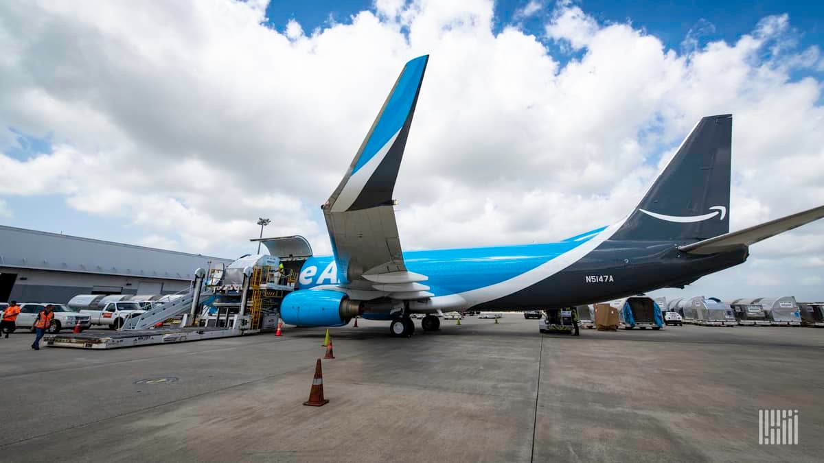 A light/dark blue Amazon Prime jet at the cargo terminal, with wing tips folded up, as viewed from the side. Amazon Air is opening new airport facilities in Hawaii.