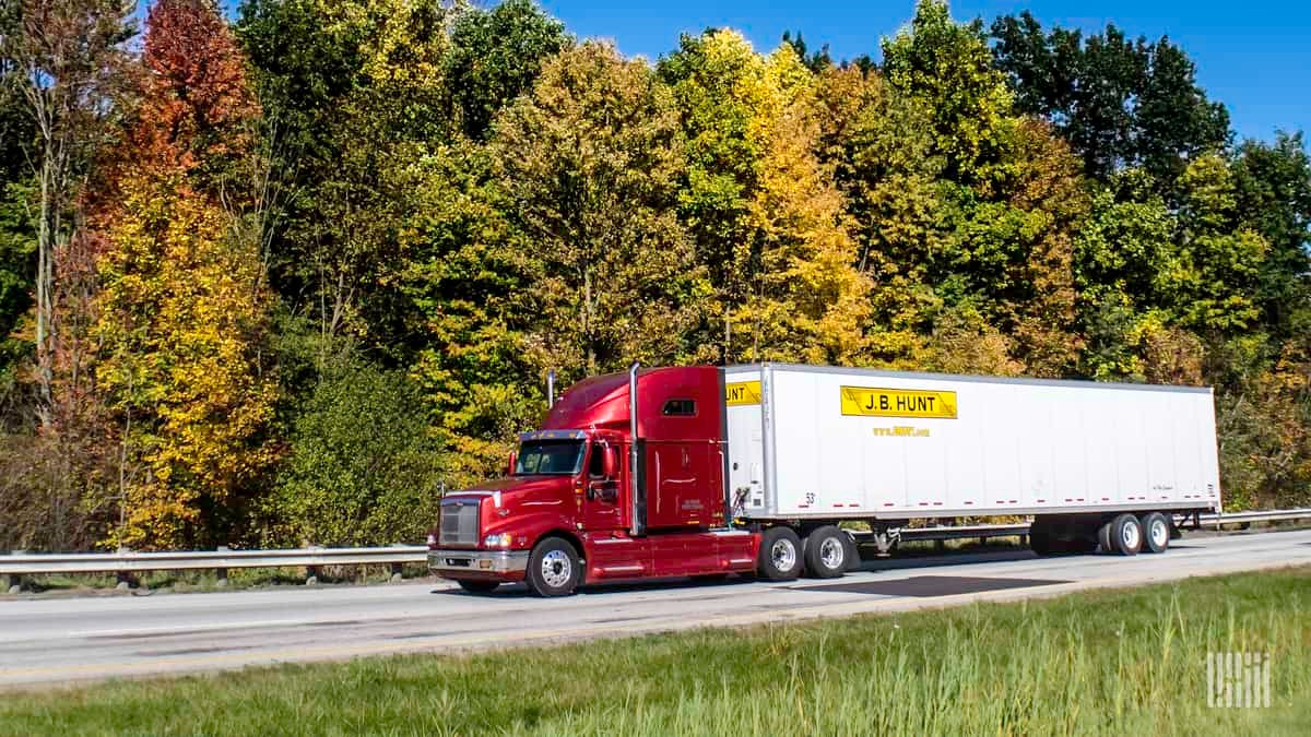 Red J.B. Hunt truck against autumnal forest