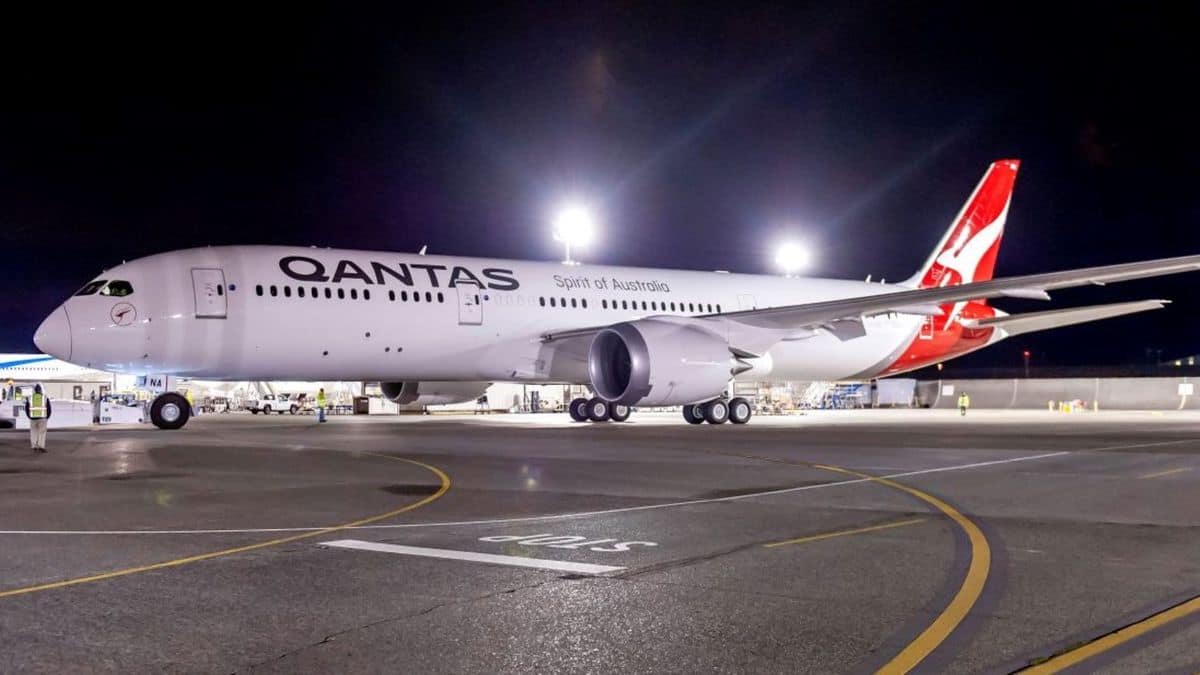 A white and red Qantas plane at airport at night. Qantas has closed a warehouse because of a COVID scare.