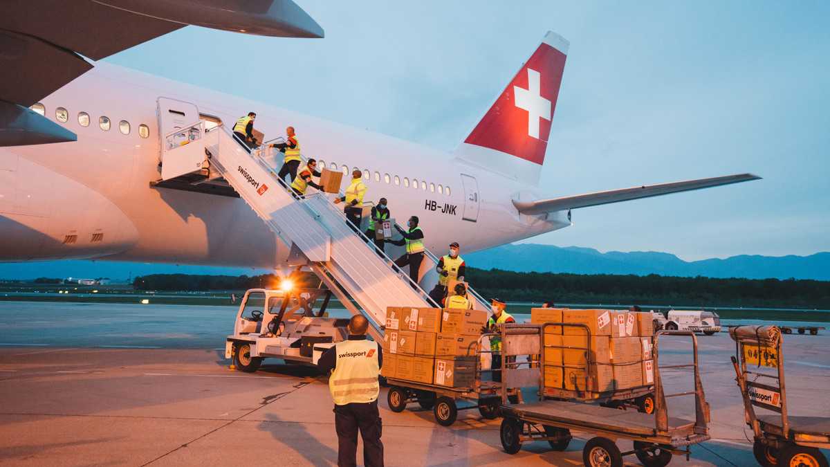 Boxes of PPE being hand-passed up the passenger stairs for loading in cabin of Swiss Air flight. Swiss Air received permission to load all kinds of commodities in the cabin.