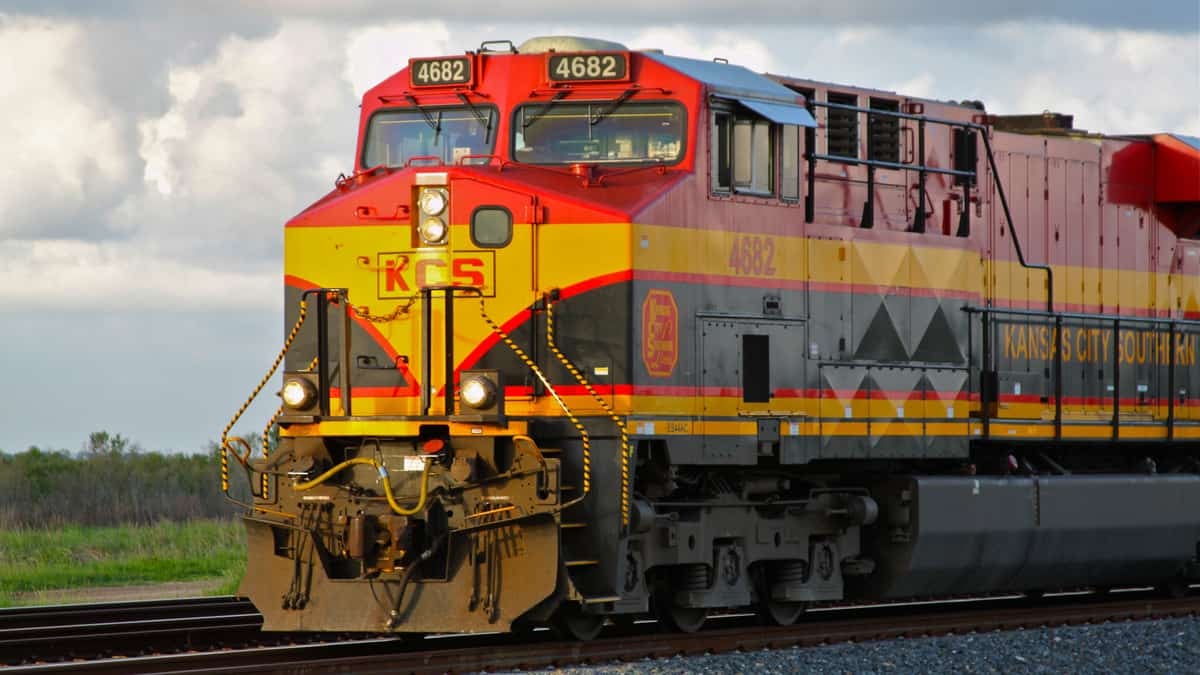 A photograph of a Kansas City Southern train traveling through an open field.