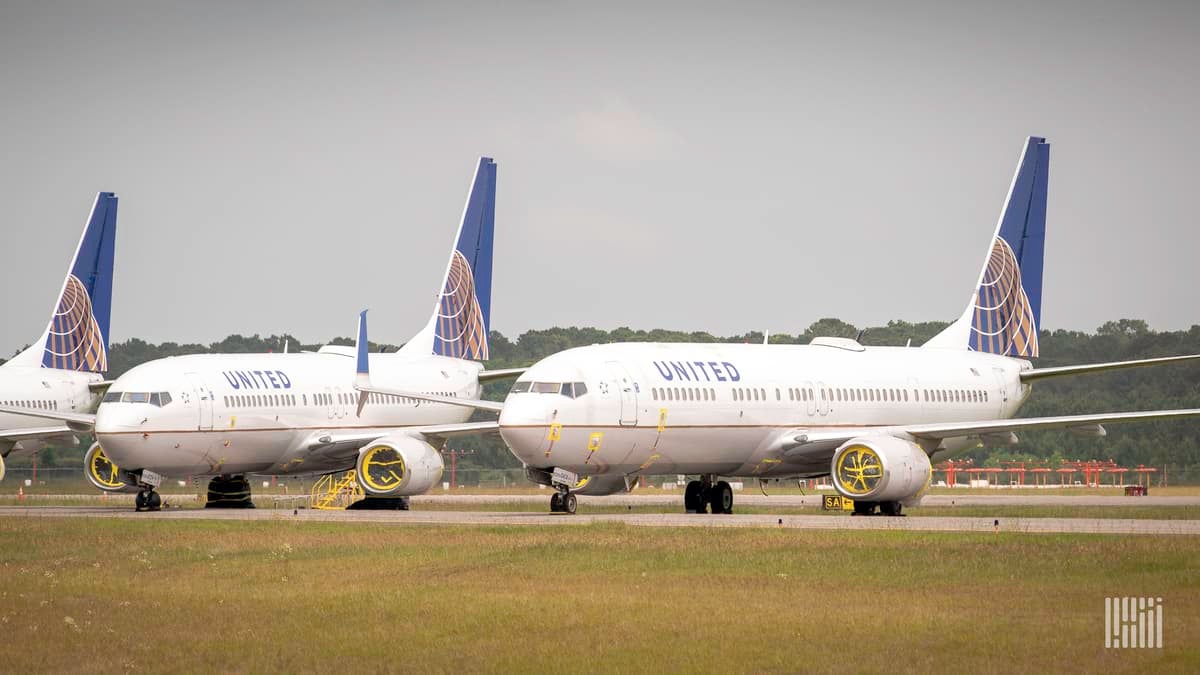 White jets, with blue tails from United sit in a row at Houston airport. They are in temporary storage during coronavirus.