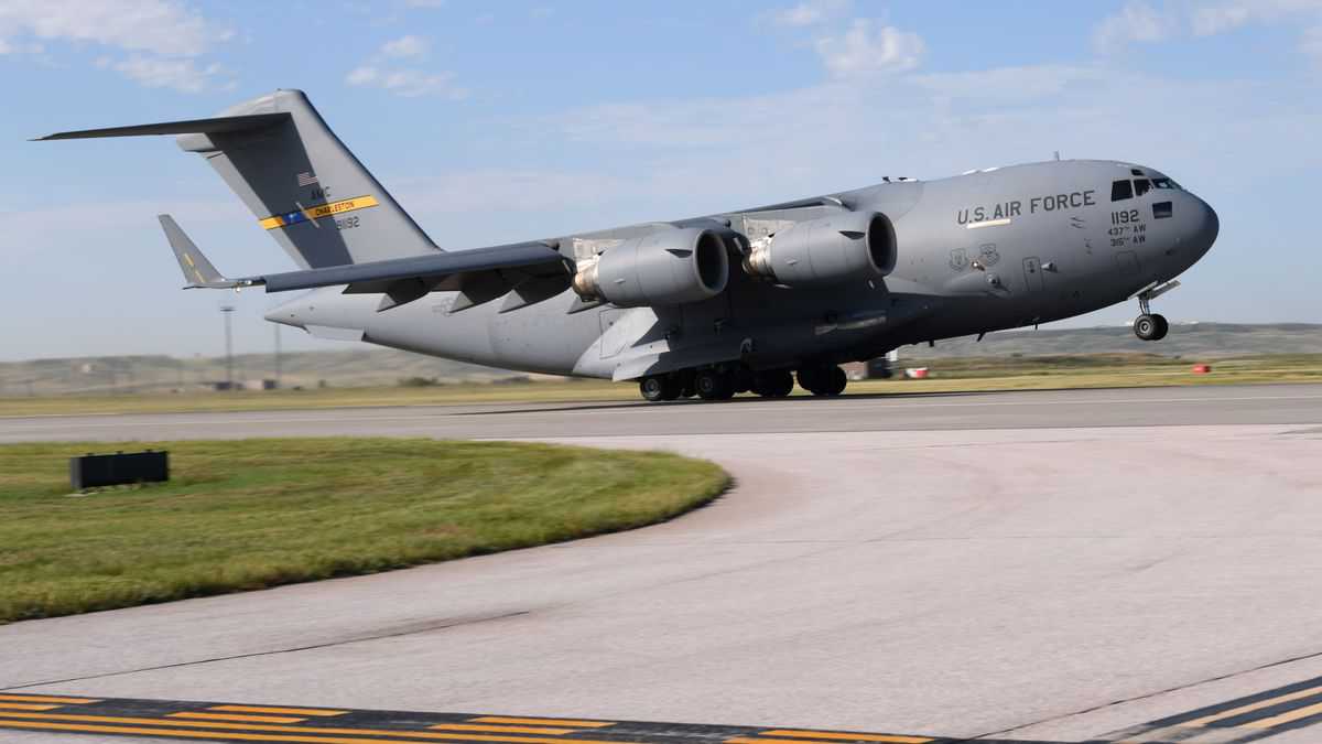 A big gray U.S. Air Force cargo jet takes off. Military planes might be used to delivery COVID vaccines.