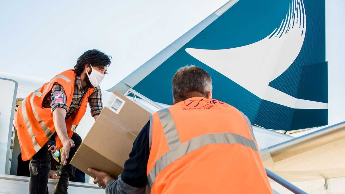 Workers unload boxes from the rear cabin door of a big jet. Handing the boxes down the stairs of Cathay Pacific plane at Pittsburgh airport.