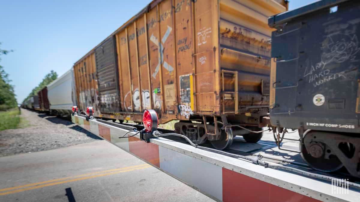 A photograph of a train at a highway grade crossing.