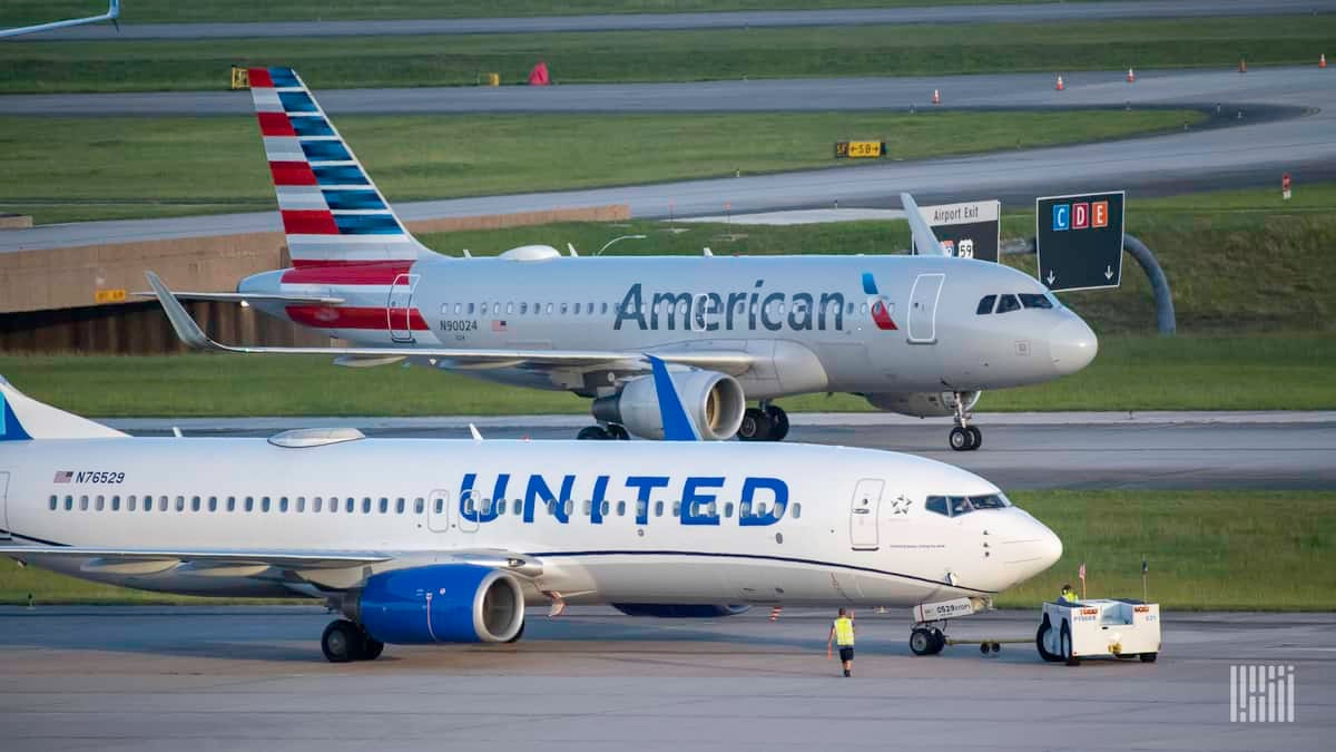 A white United Airlines jet and silver American Airlines jet on adjacent taxiways. Airlines face a financial crisis because of COVID.