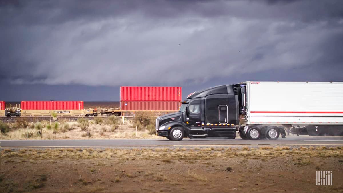 Truck on highway with intermodal train in background