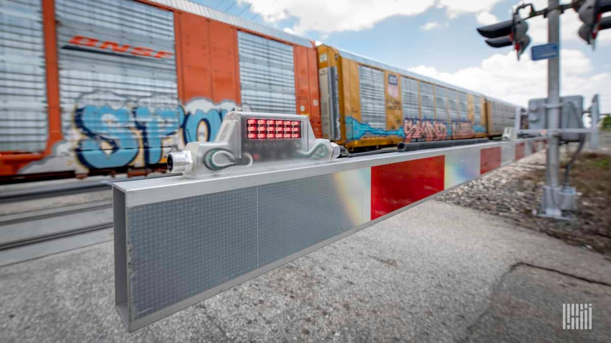 A photograph of a train passing by a rail crossing.