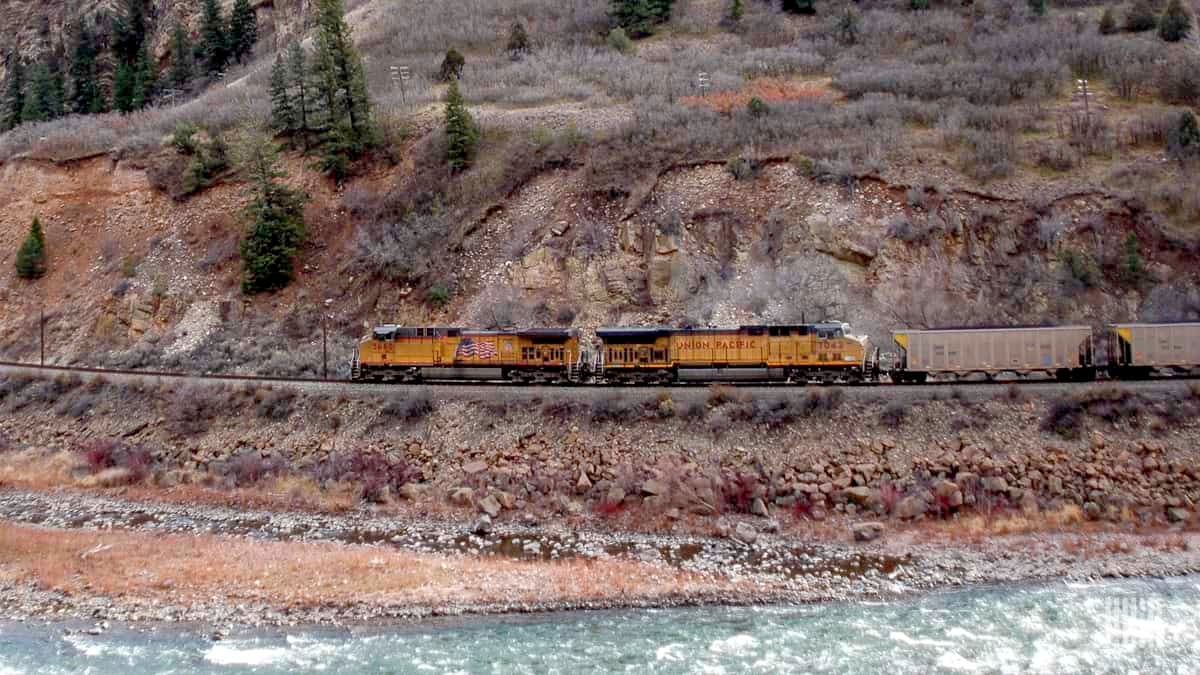 A photograph of a Union Pacific train traveling by a rocky mountainside.