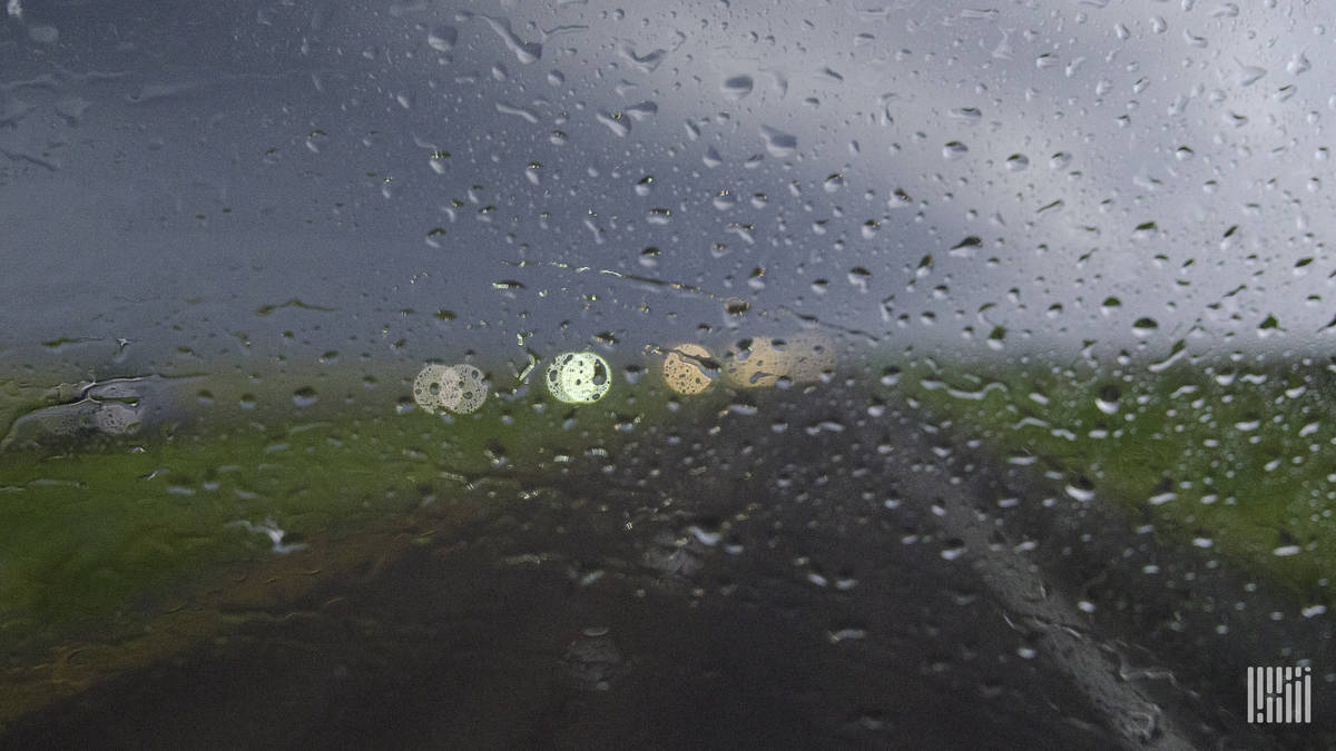 Heavy rain falling on windshield, as seen from inside a tractor-trailer.