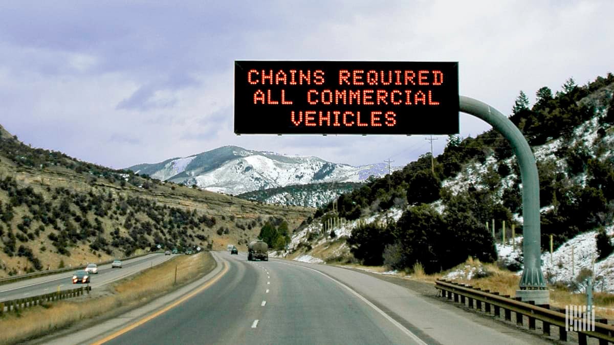 "Chains required" road sign along a snowy mountain road.