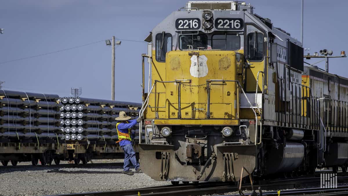 A photograph of a rail worker climbing a Union Pacific train.