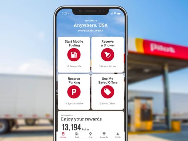 Close-up of phone with driver app in front of Pilot gas station