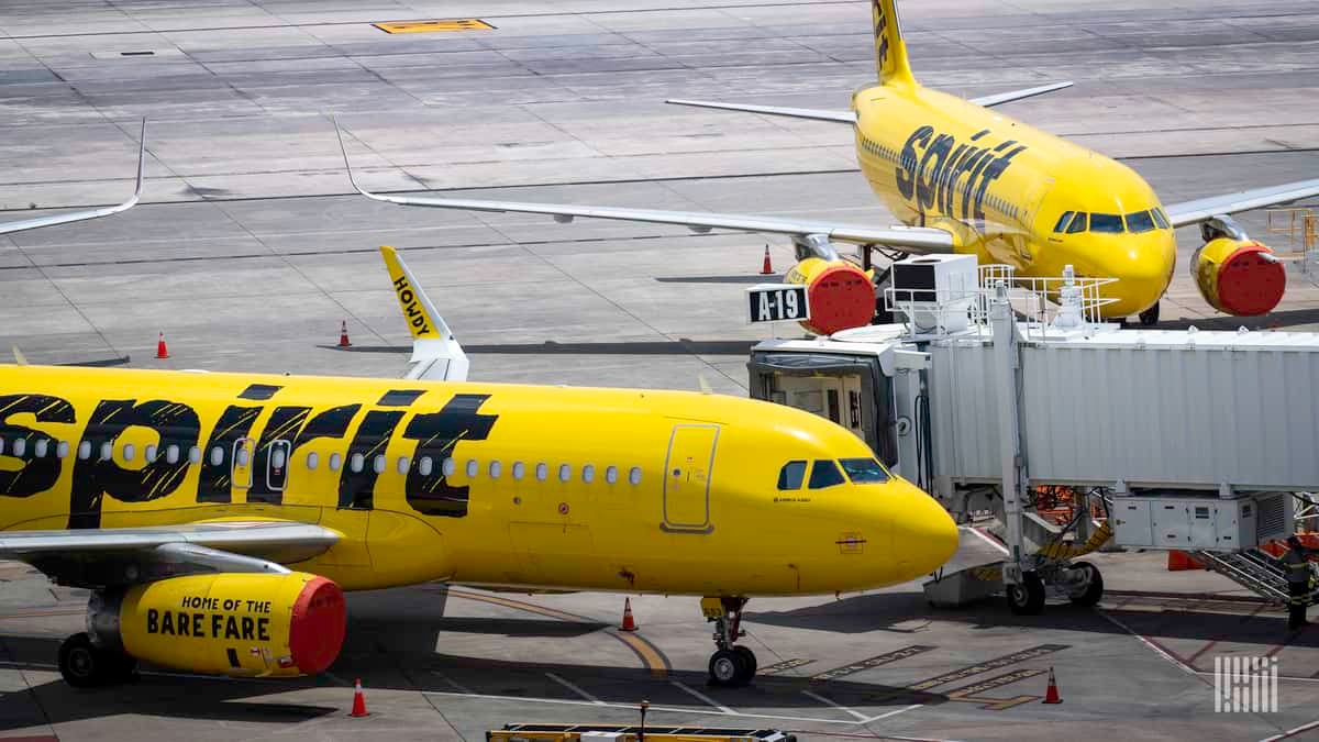 Yellow planes from Spirit Airlines parked at airport with engine covers because they are not being operated.