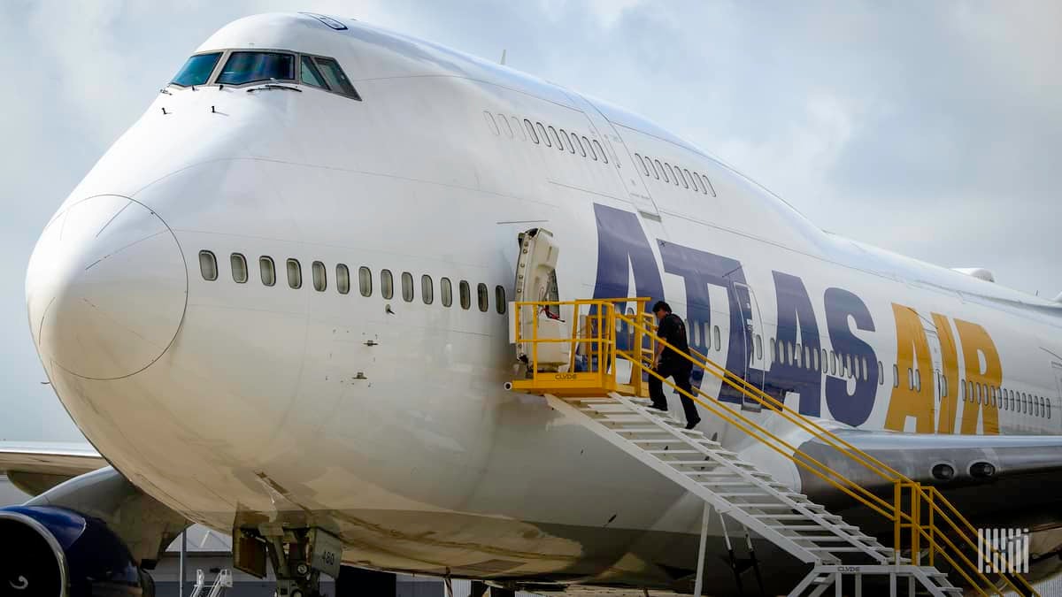 A white Atlas Air jumbo jet, with man walking up stairs into side door.