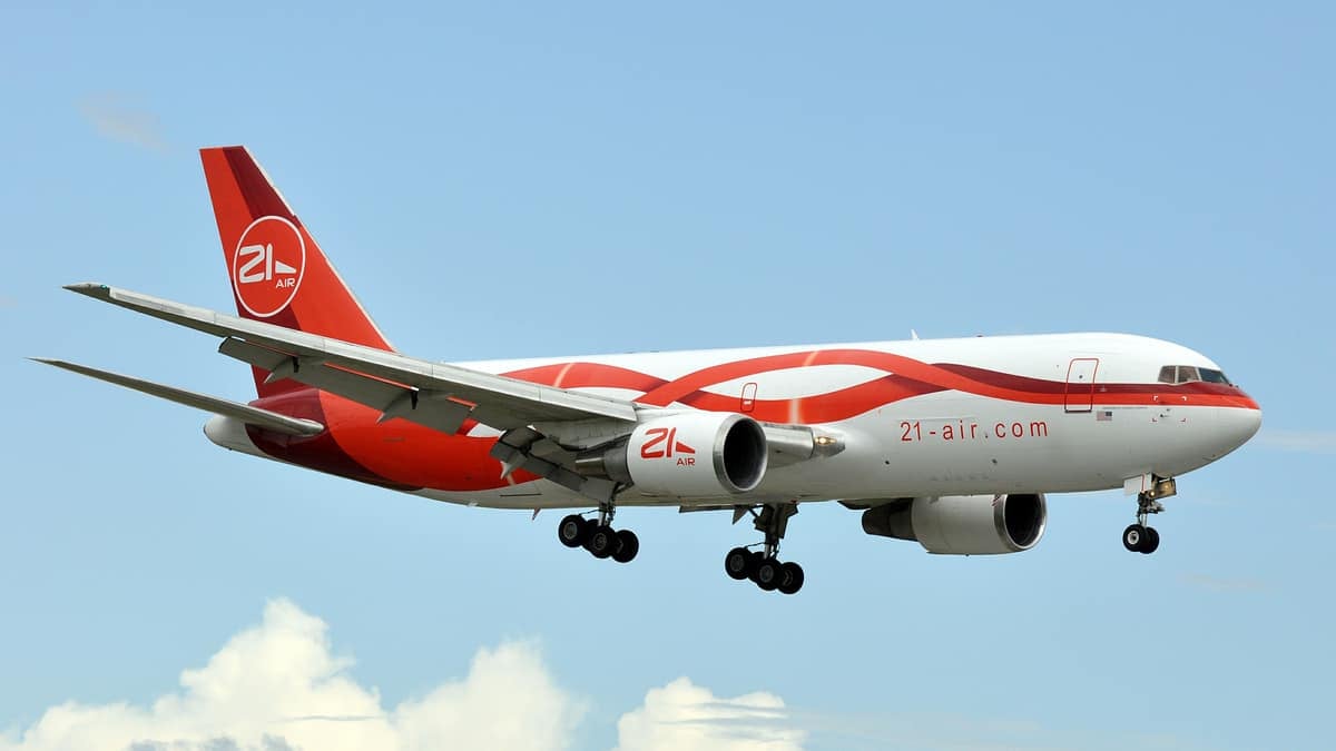 A red-and-white jet comes in for landing with wheels retracted. 21 Air is a small cargo carrier that flies planes for DHL.