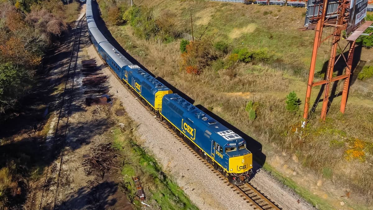 A photograph of a CSX train winding through a field.