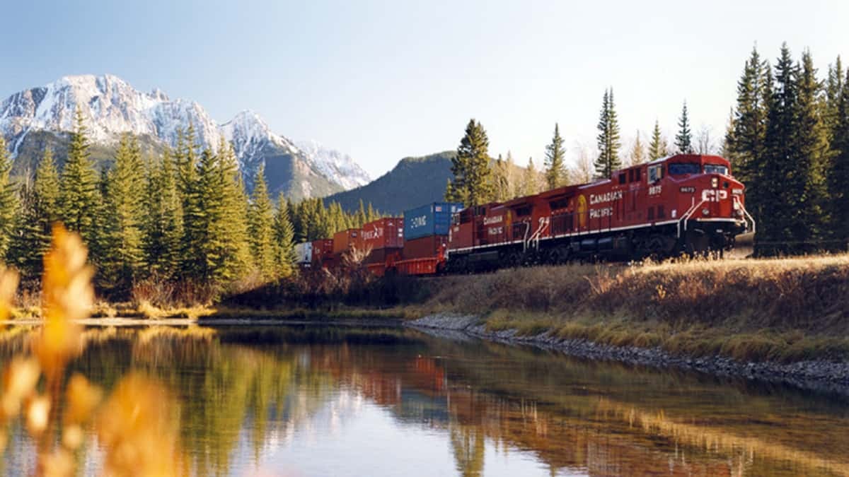 A photograph of a Canadian Pacific train traveling by a lake.