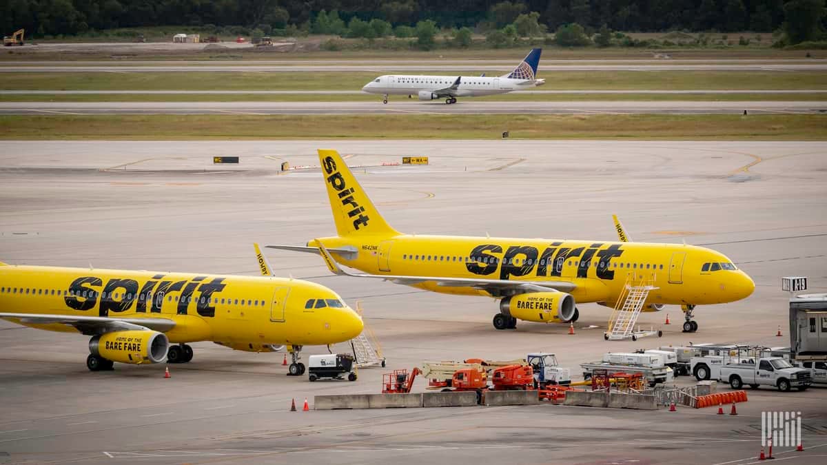 Bright yellow Spirit planes at the airport gate.