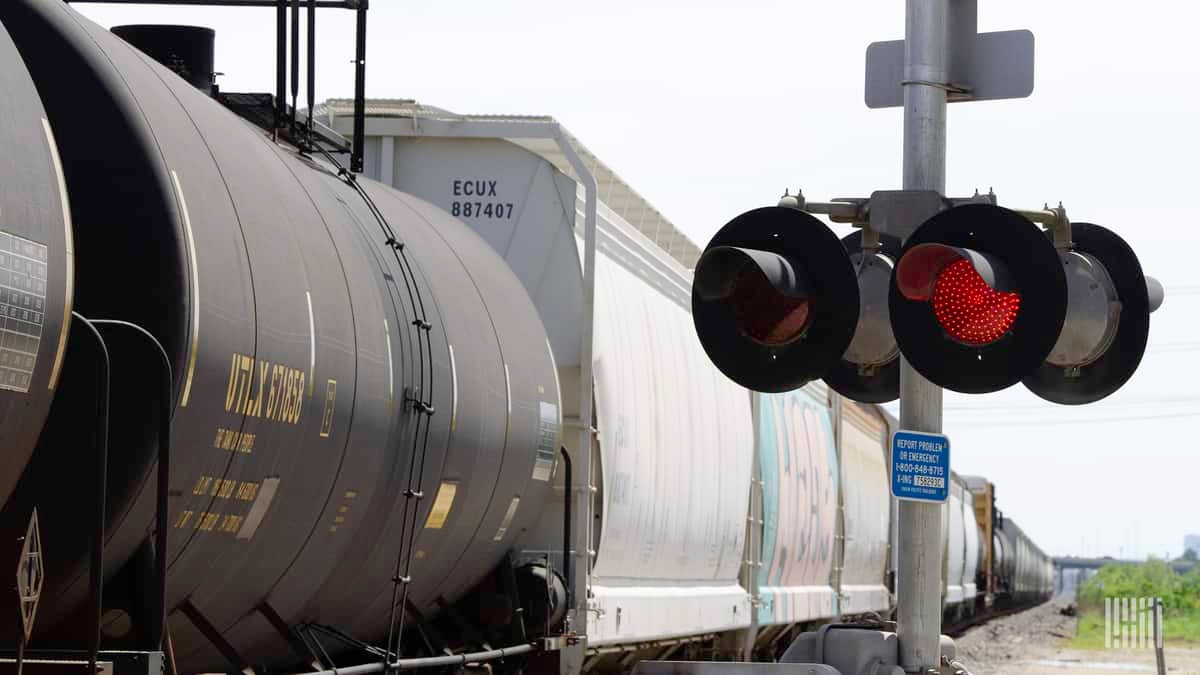 A photograph of a train passing by a rail crossing.