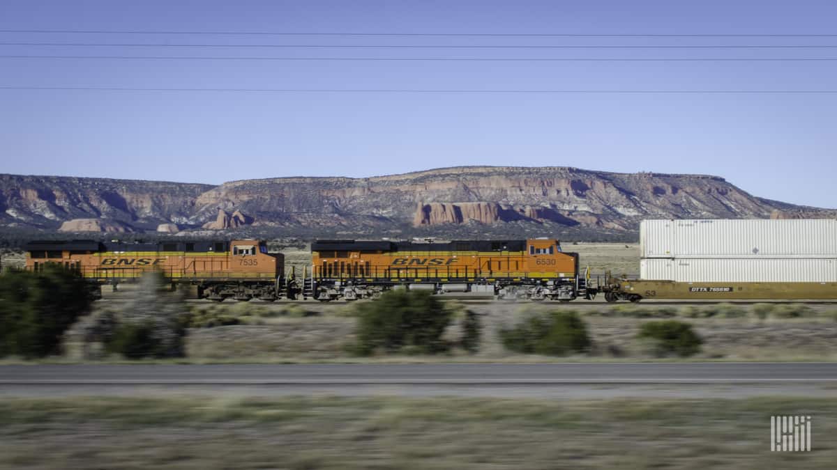 A photograph of a BNSF train traveling by a mountain range.