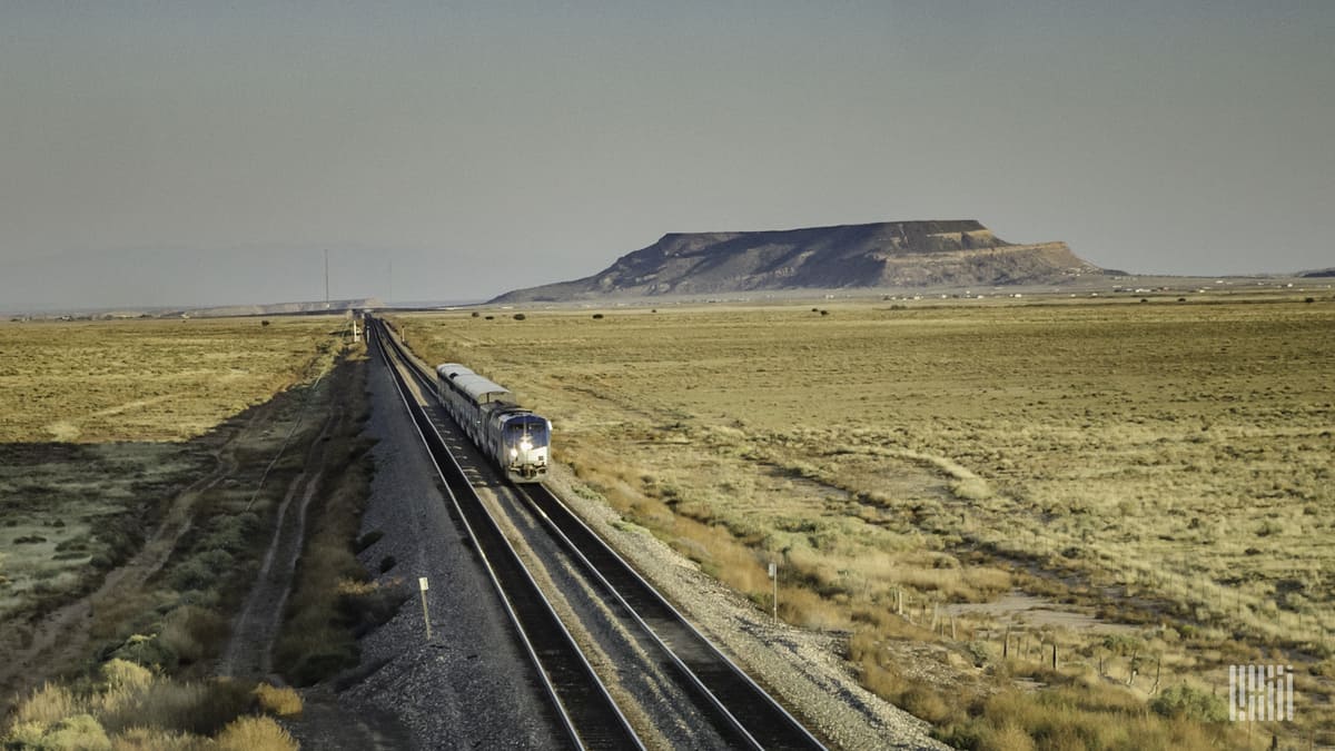 A photograph of a train traveling through a desert.