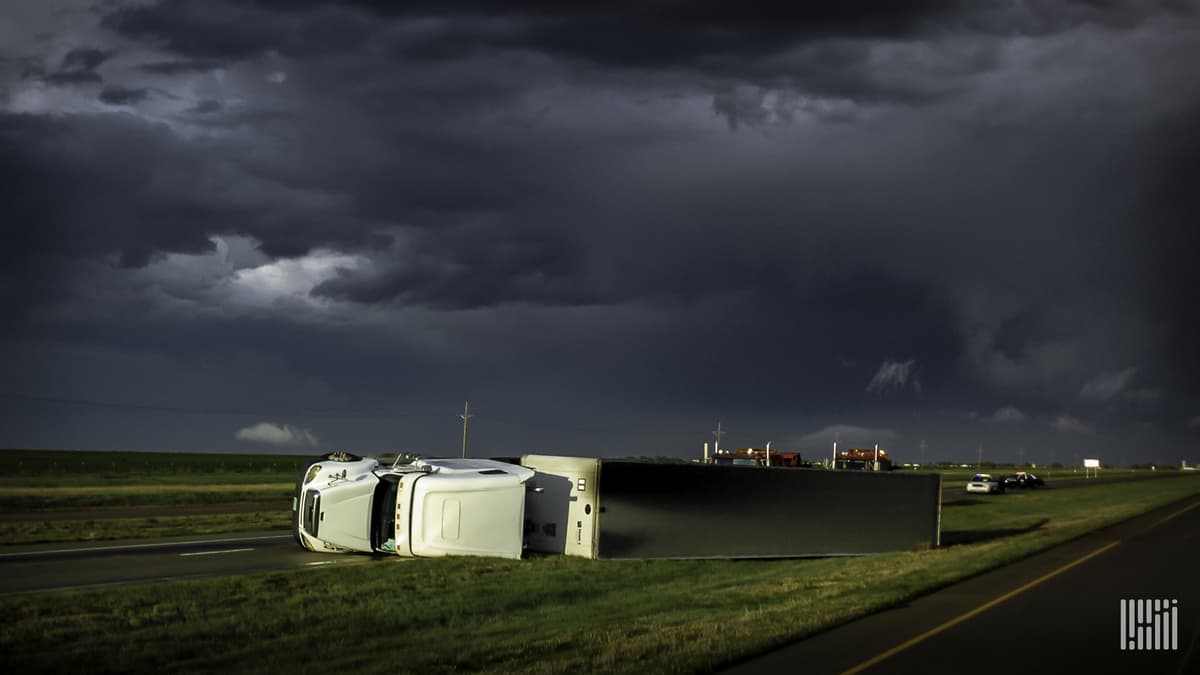 Tractor-trailer blown over along a highway.