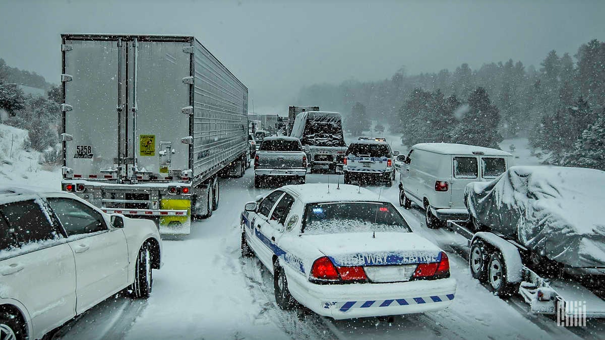 Tractor-trailers an other vehicles in a traffic jam on a snowy highway.