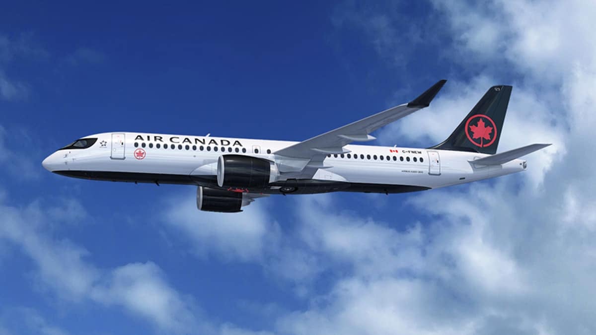 A white Air Canada jet streaks across sky with white clouds in background.